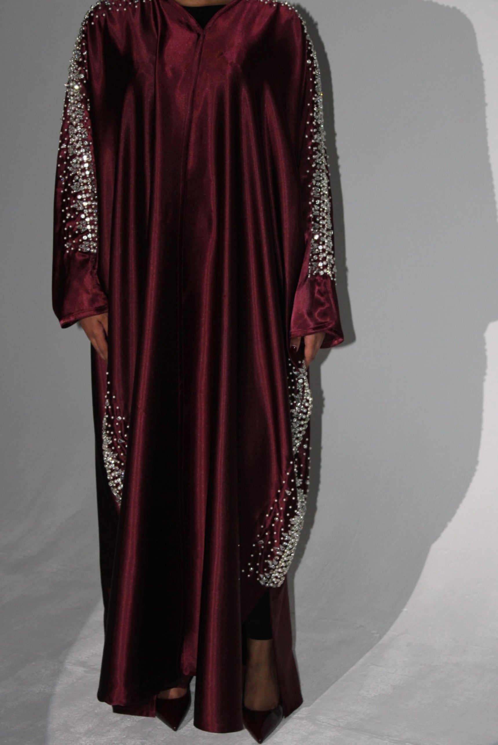 Maroon abaya with silver embellishments on sleeves against a gray background