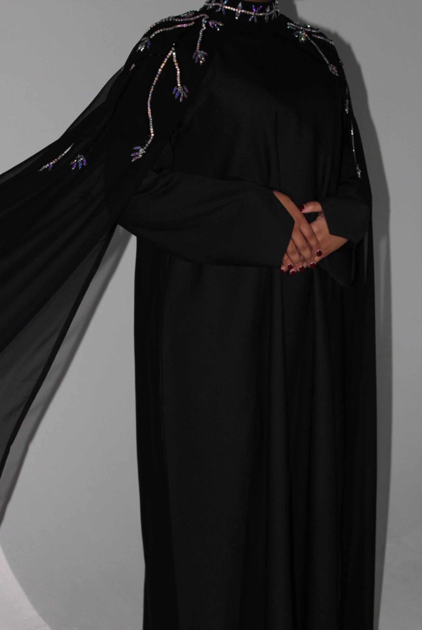 Black abaya with intricate detailing on a plain background