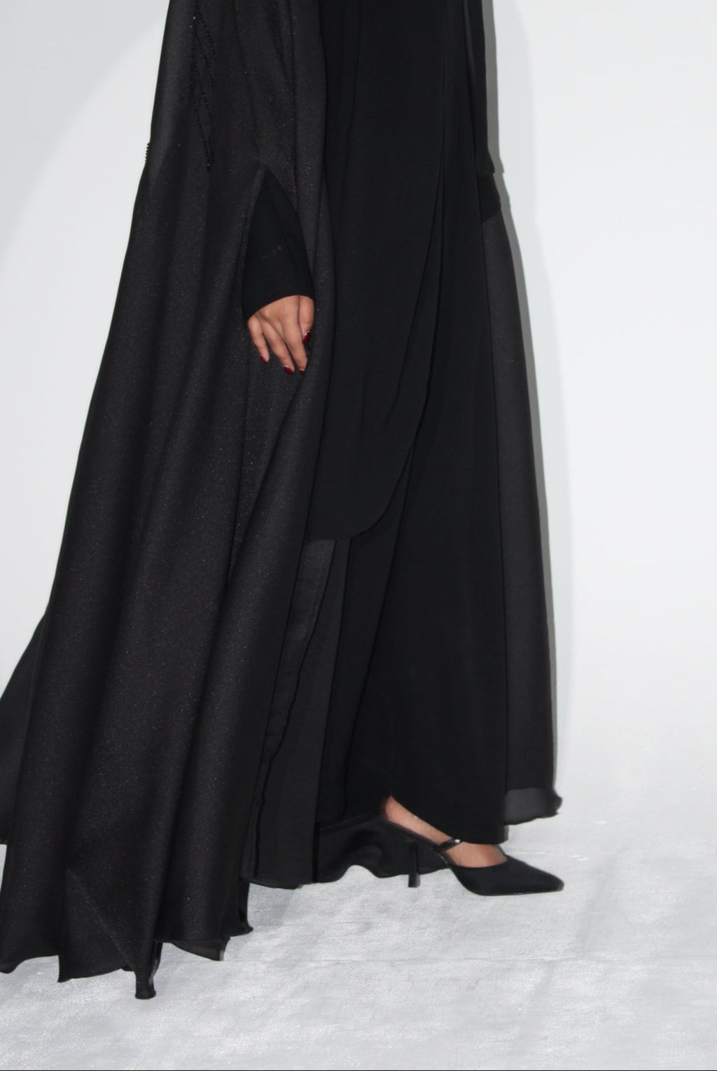 Black abaya worn by a person on a white background