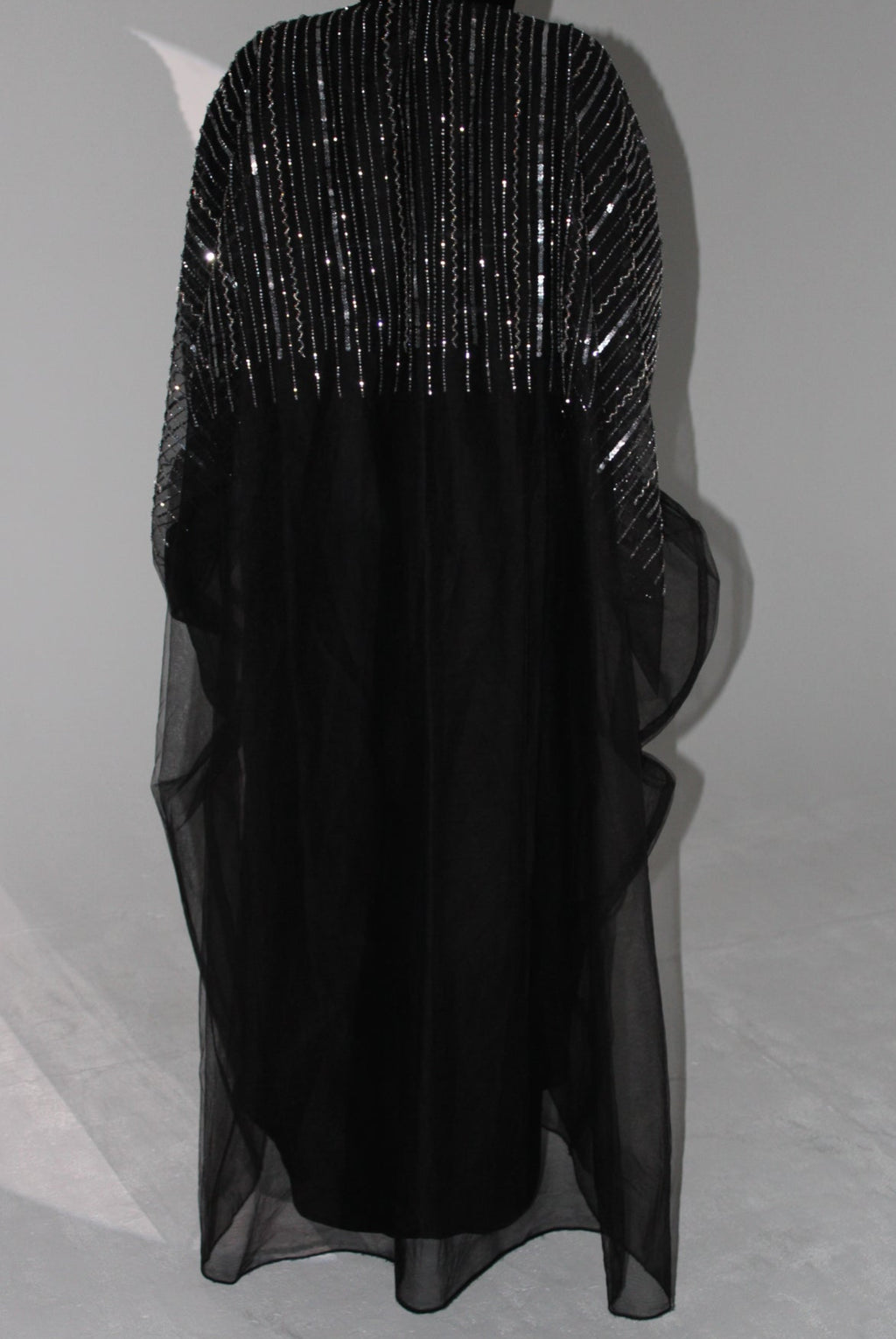Black abaya dress with sheer overlay on a light gray background