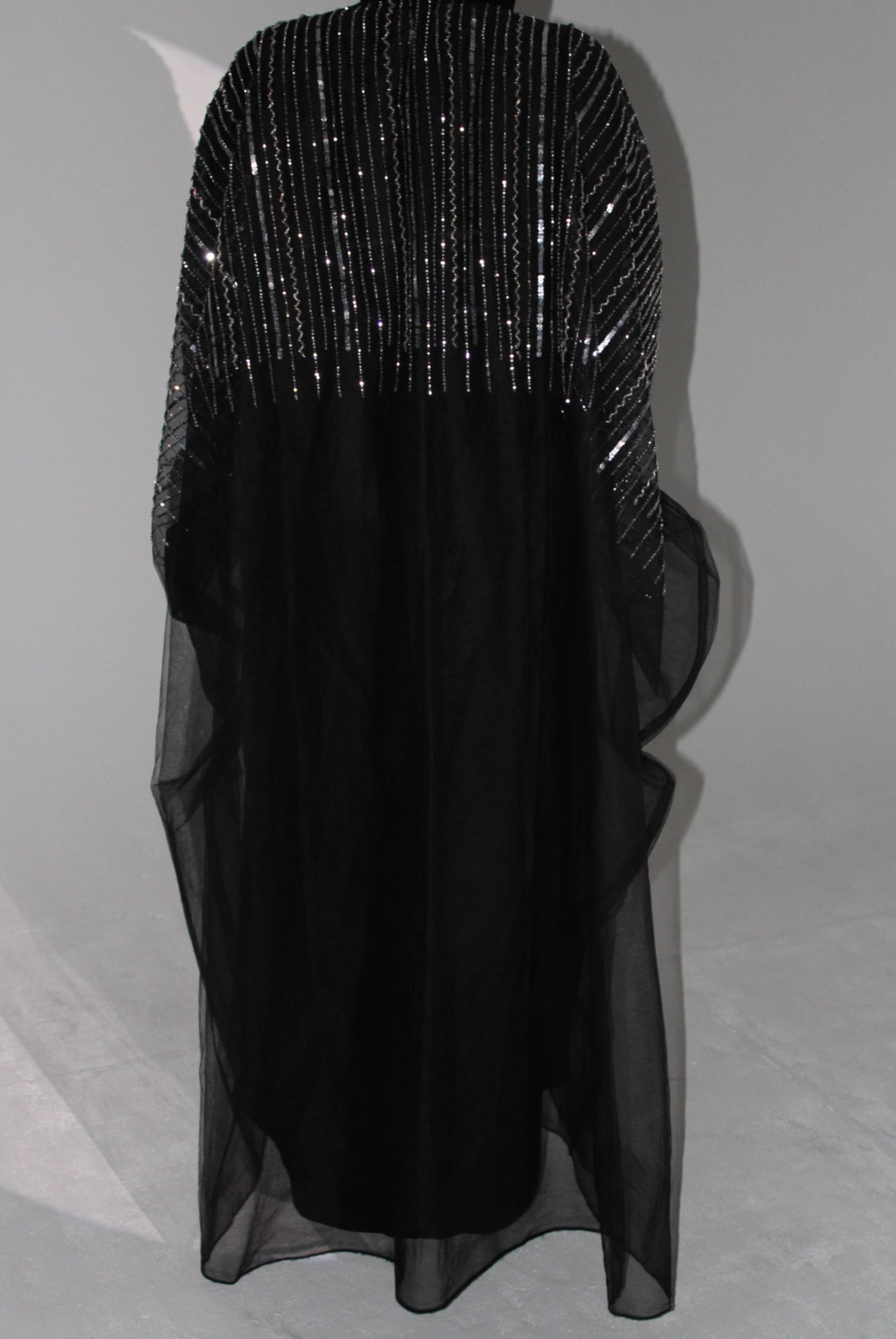 Black abaya dress with sheer overlay on a light gray background