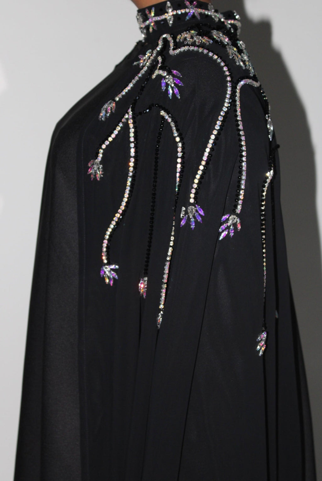 Black abaya with intricate beadwork on a plain background