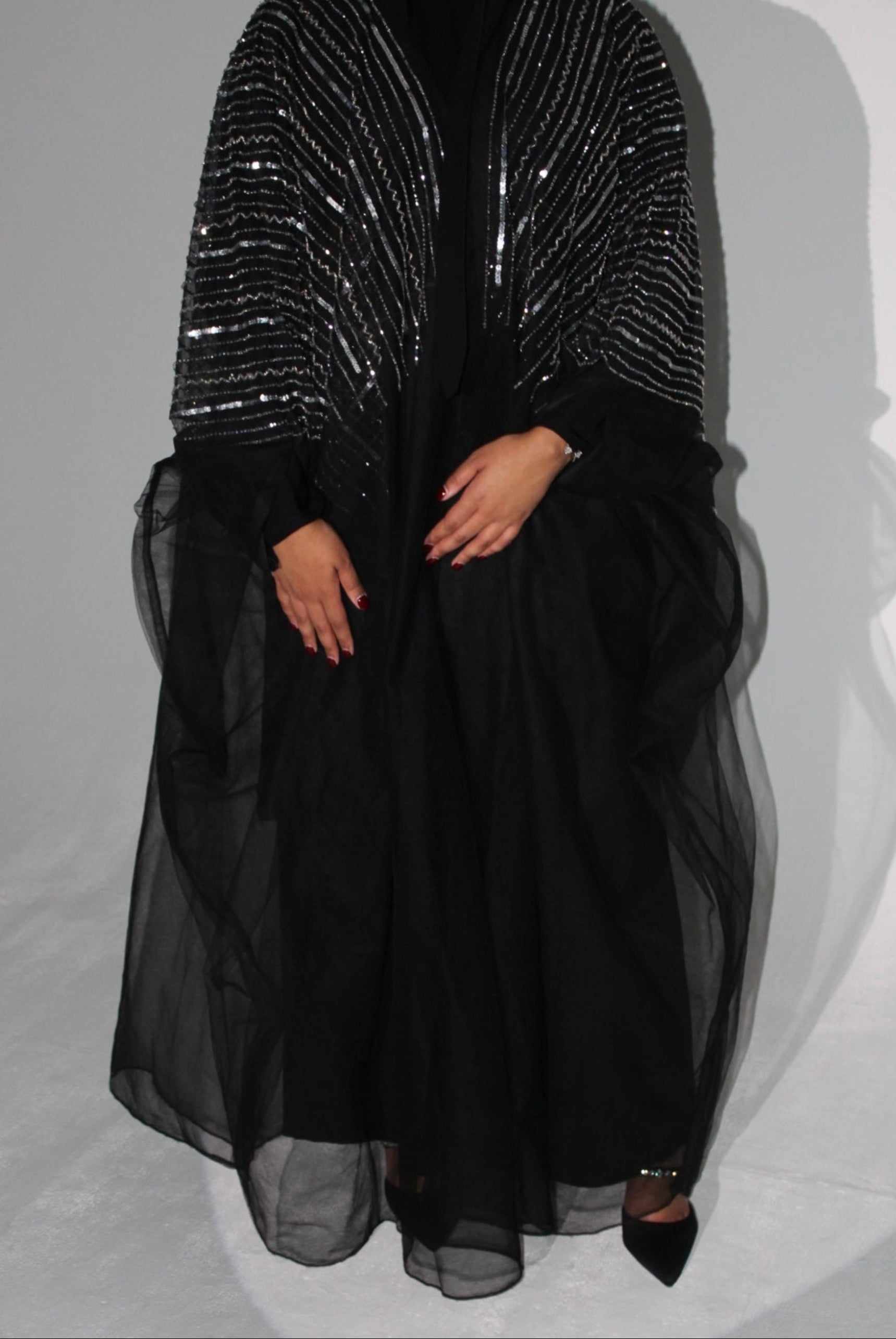 Black abaya dress with a sequined top on a white background