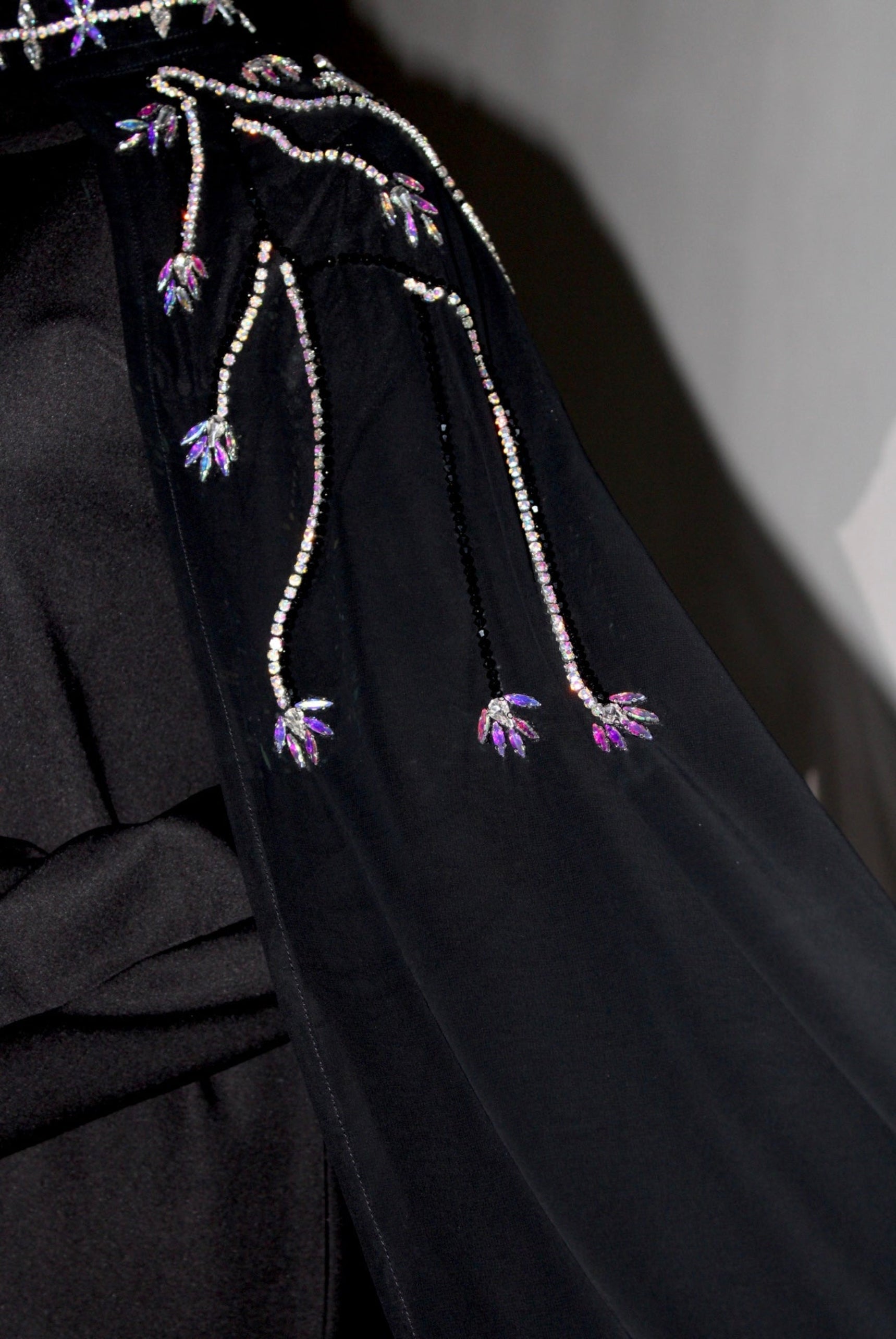 Black garment with floral embellishments and beads on a plain background