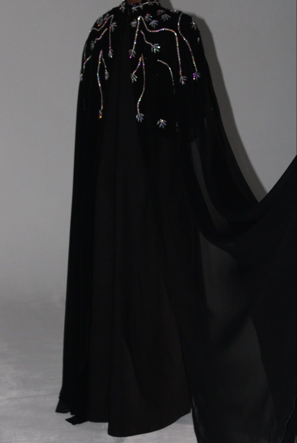 Black abaya fabric with intricate beadwork on a plain background