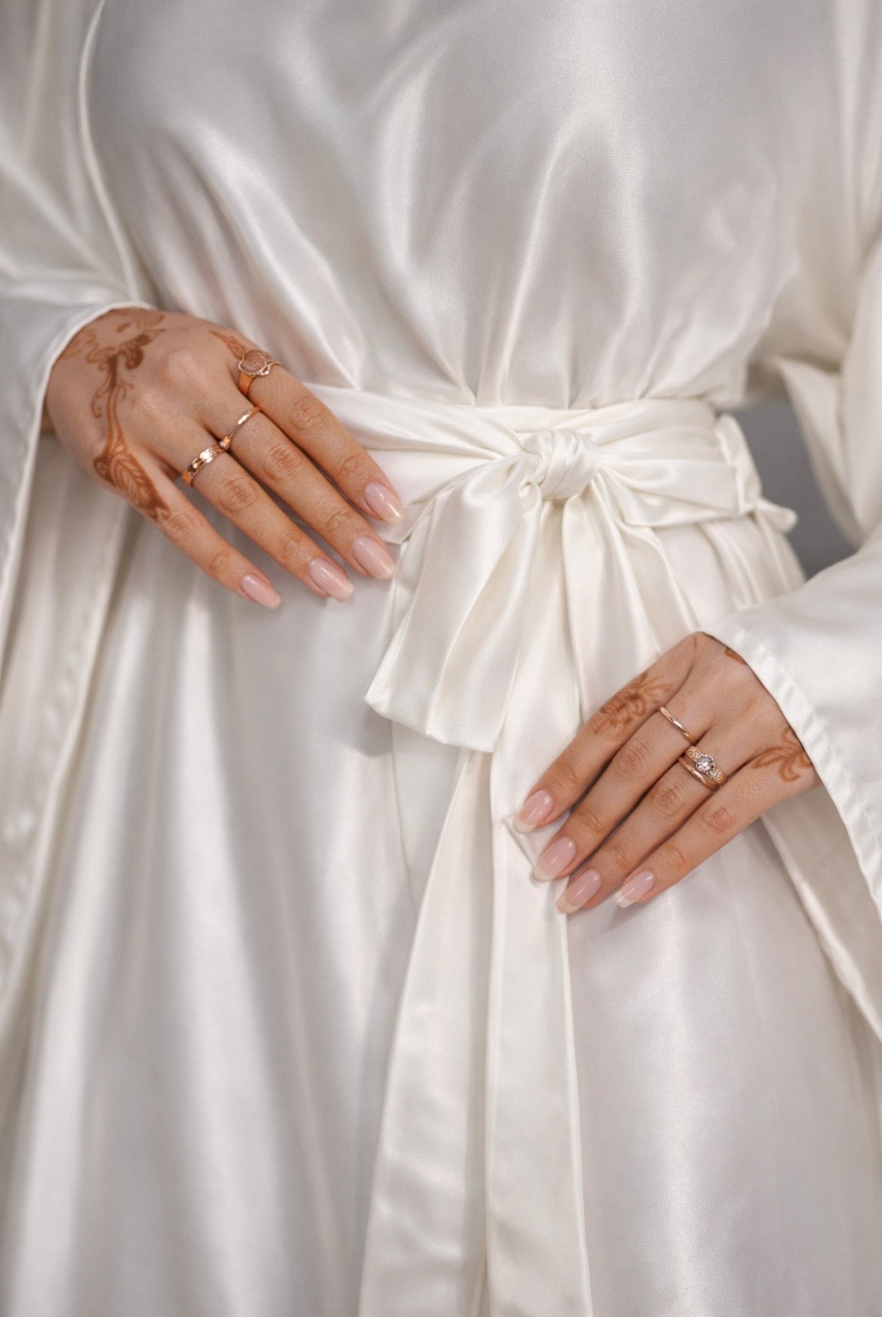 Close-up of a person wearing a white dress with hands adorned with rings.