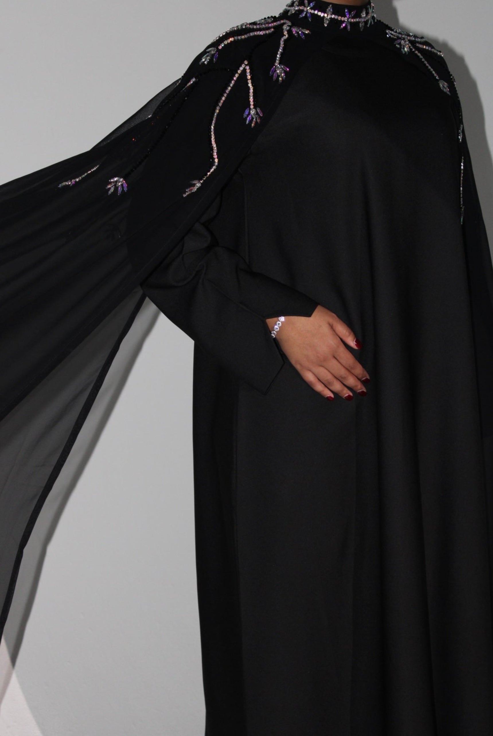 Black abaya with intricate detailing on a plain background