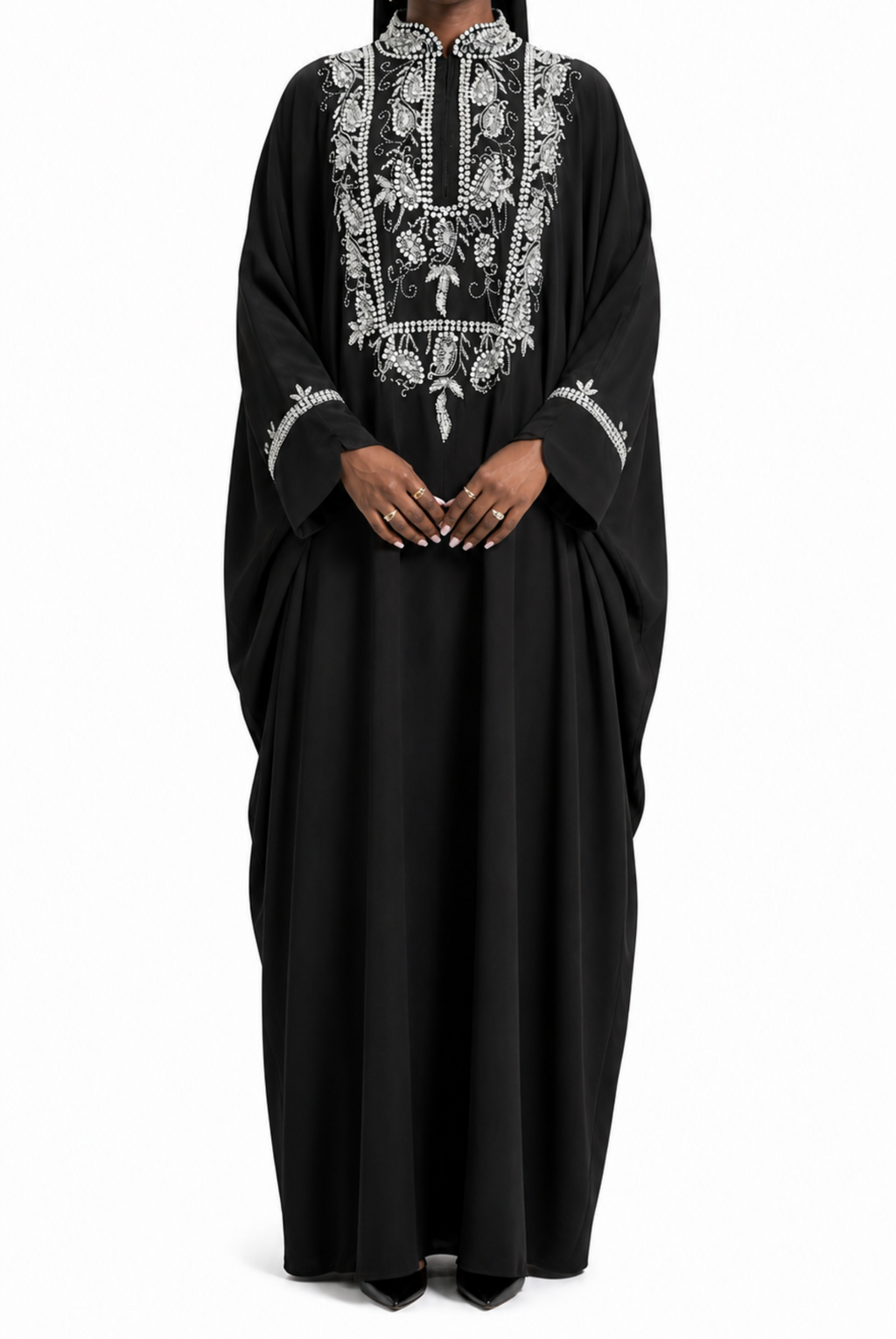Woman wearing a black abaya with white embroidery on a white background