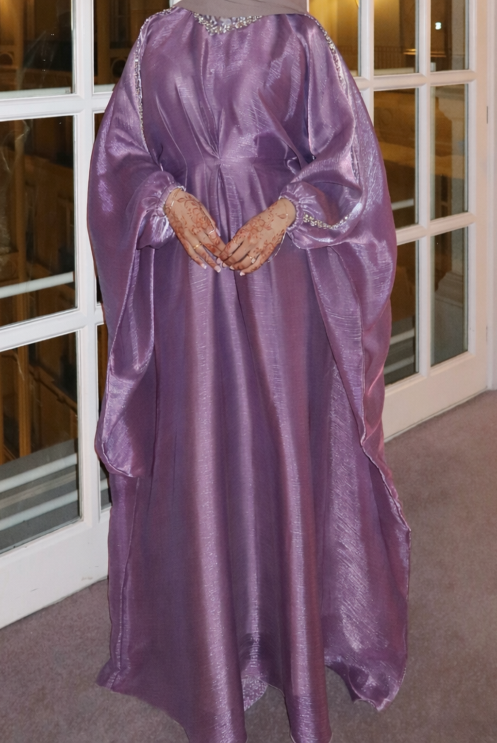 Purple satin gown with embellishments on a mannequin in front of a glass door.