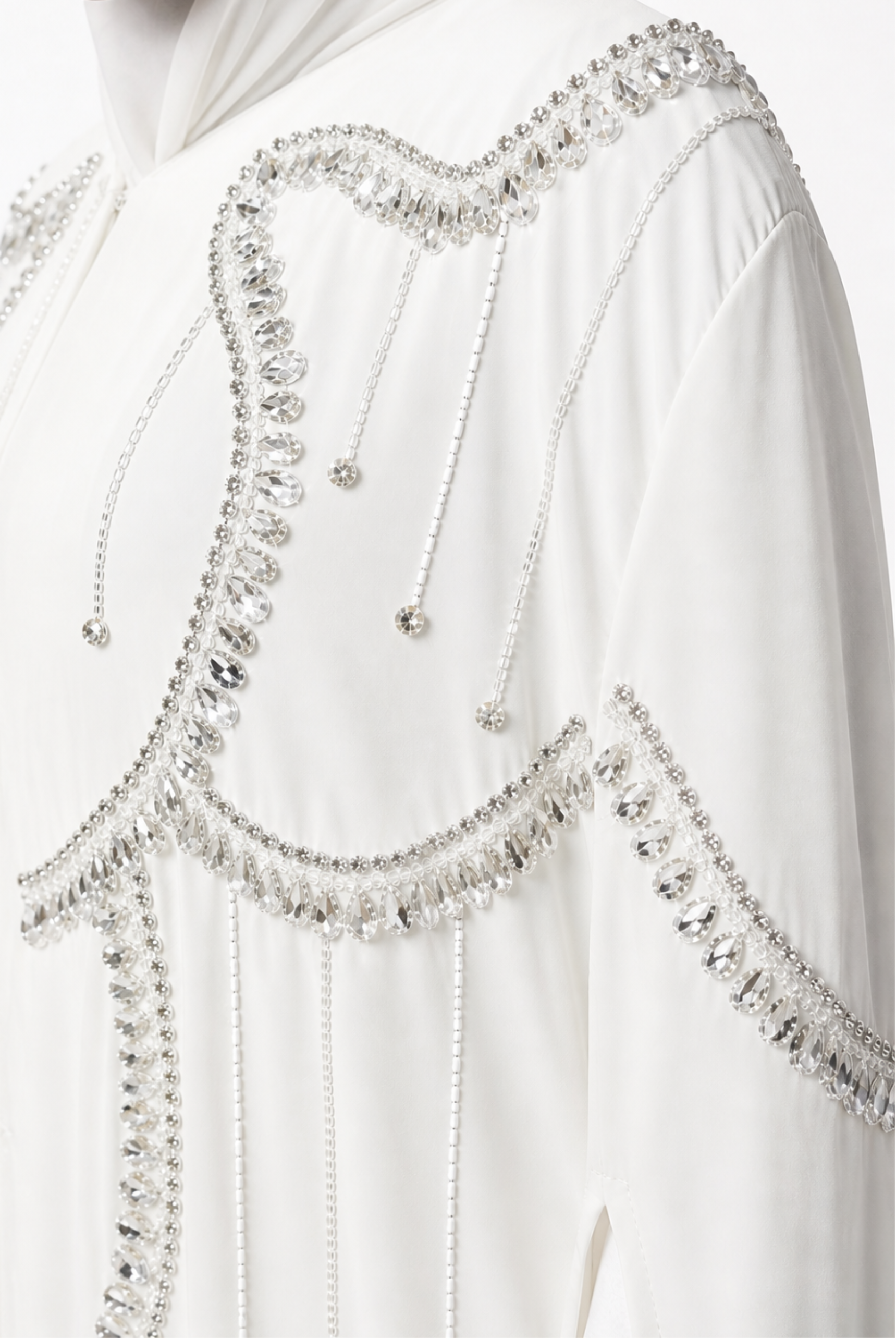 White garment with intricate silver beadwork on a plain background