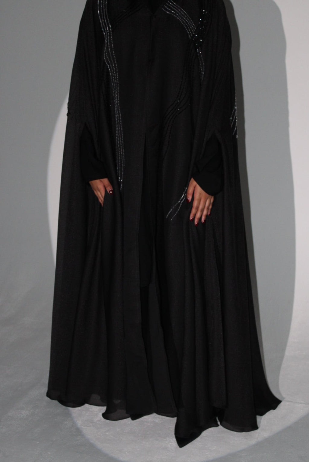 Black luxury abaya with intricate detailing on a gray background