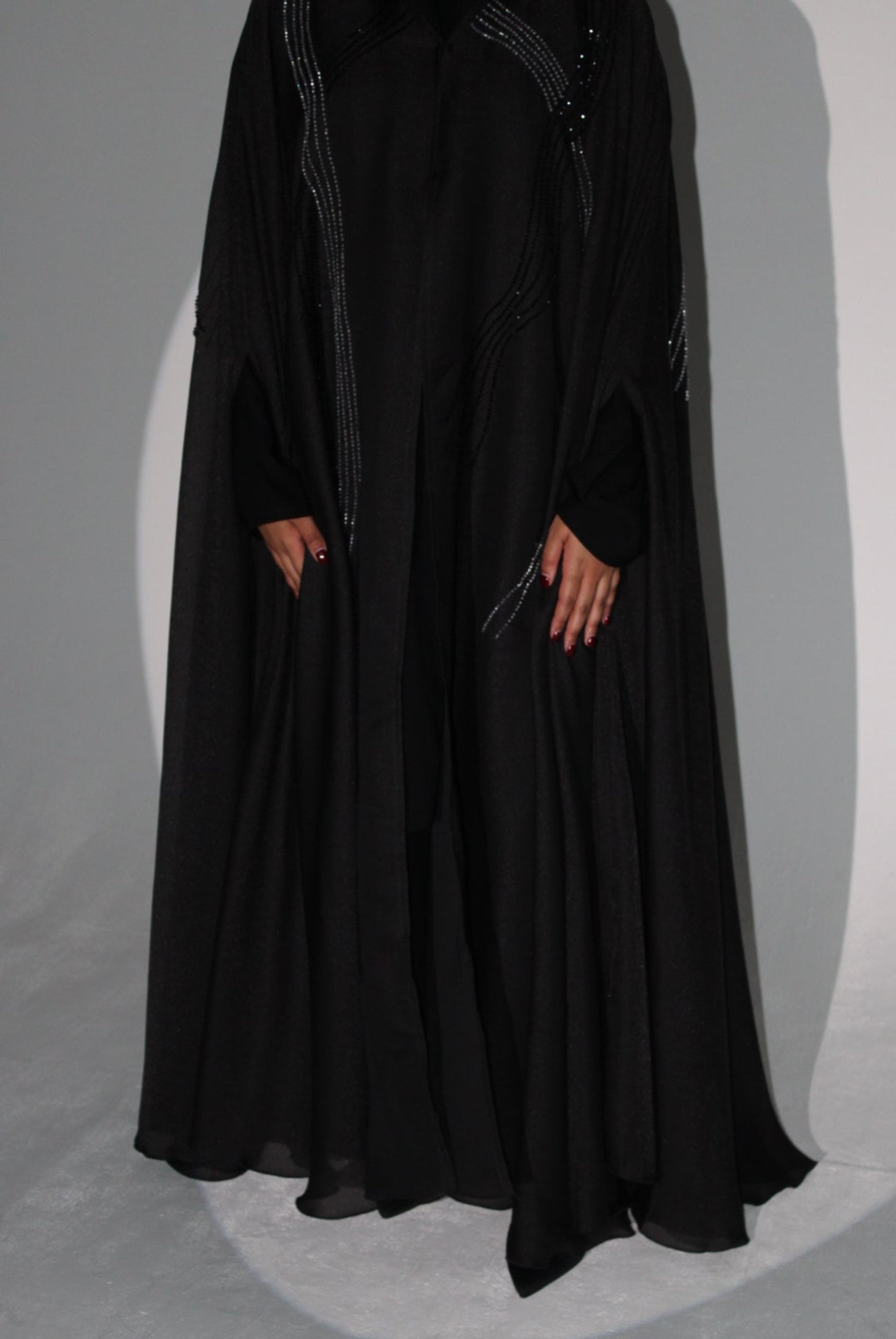 Black luxury abaya with intricate detailing on a gray background