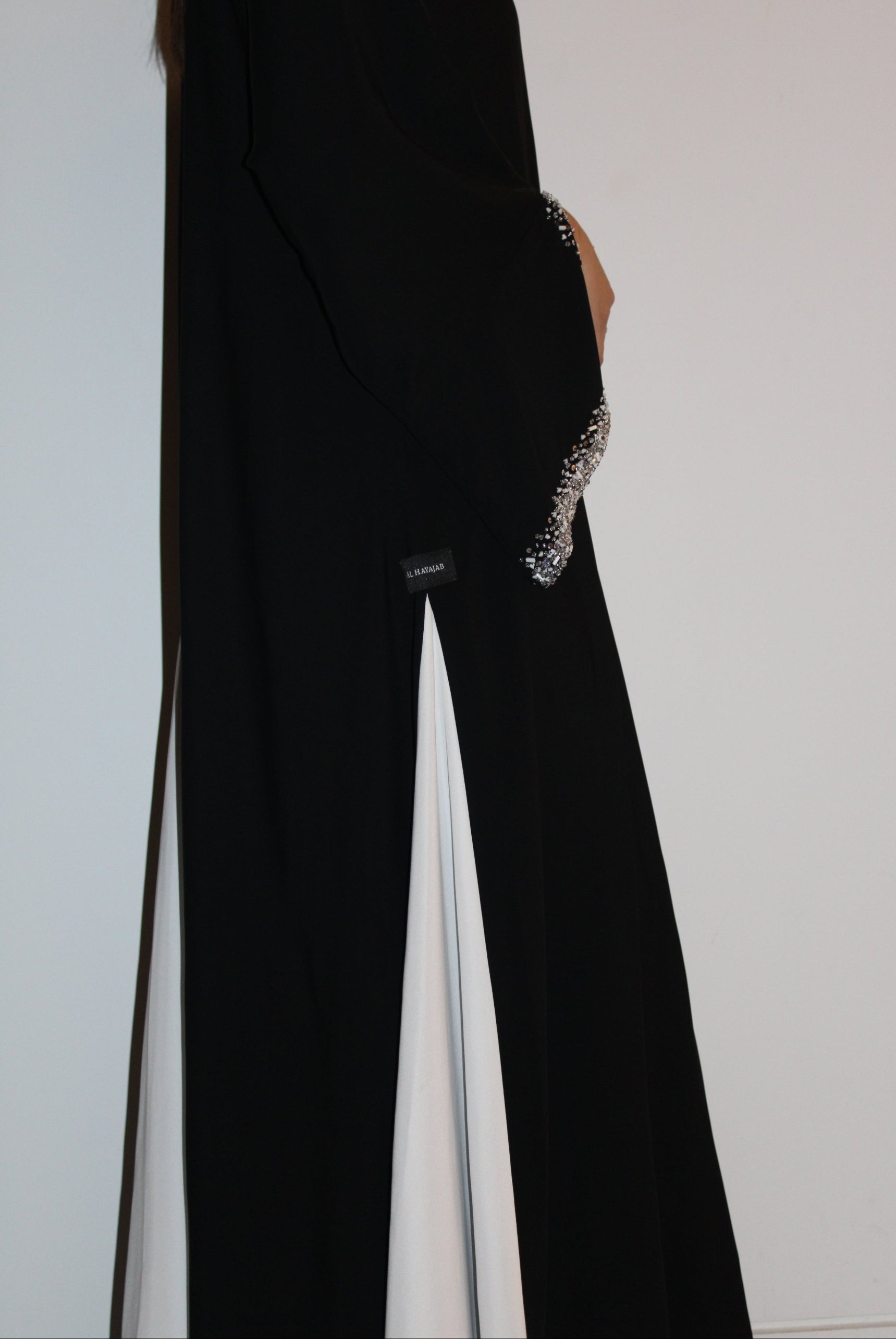 Black abaya with a high slit and decorative cuffs on a white background