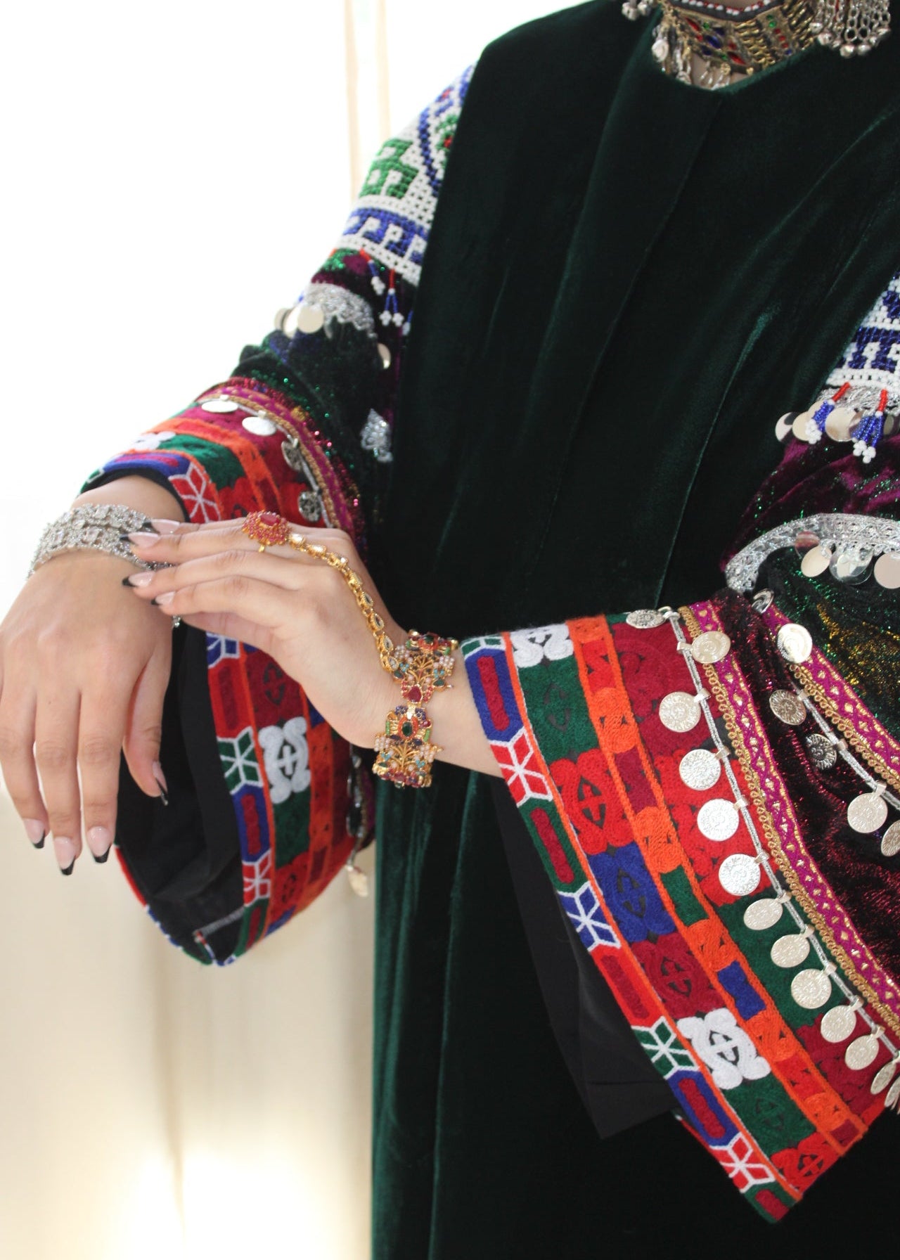 Traditional embroidered garment with colorful patterns and a hand wearing a bracelet.