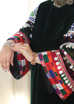 Load image into Gallery viewer, Traditional embroidered garment with colorful patterns and a hand wearing a bracelet.
