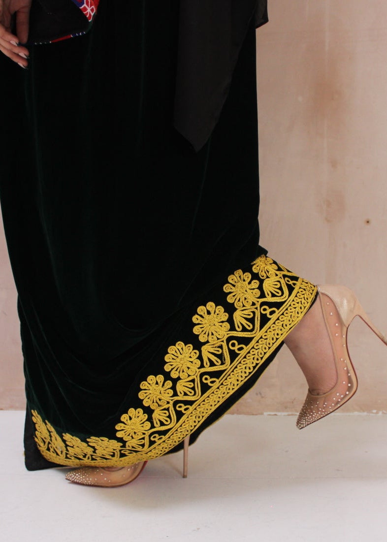 green traditional afghan dress with yellow embroidery and beige high heels on a white background